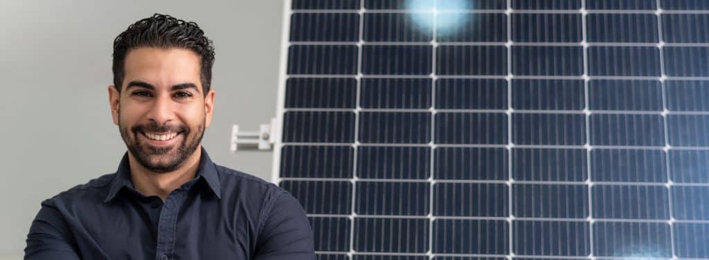 Lächelnder Projektleiter vor einem großen Photovoltaik-Modul.